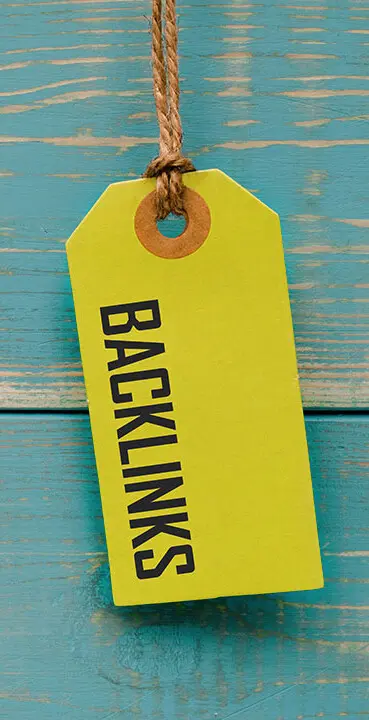 Gelbes Preisschild mit der schwarzen Aufschrift 'BACKLINKS' auf blau gestrichenem Holzuntergrund