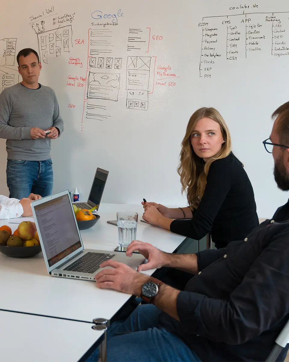 Mehrere Personen sitzen gemeinsam an einem Tisch und besprechen Unterlagen in einem Büro